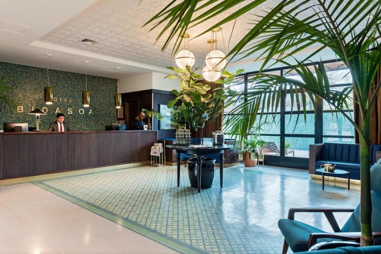 Hotel lobby with reception desk, palm plants and patterned tile floor