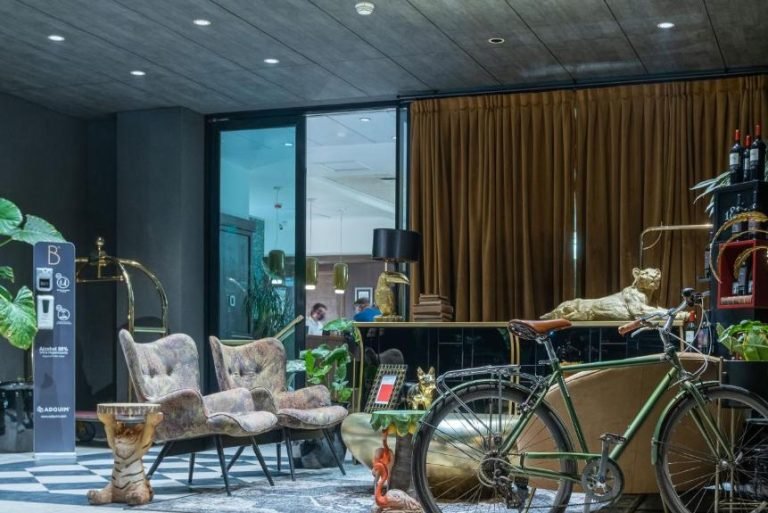 Hotel lounge with velvet armchairs, plants and a vintage bicycle