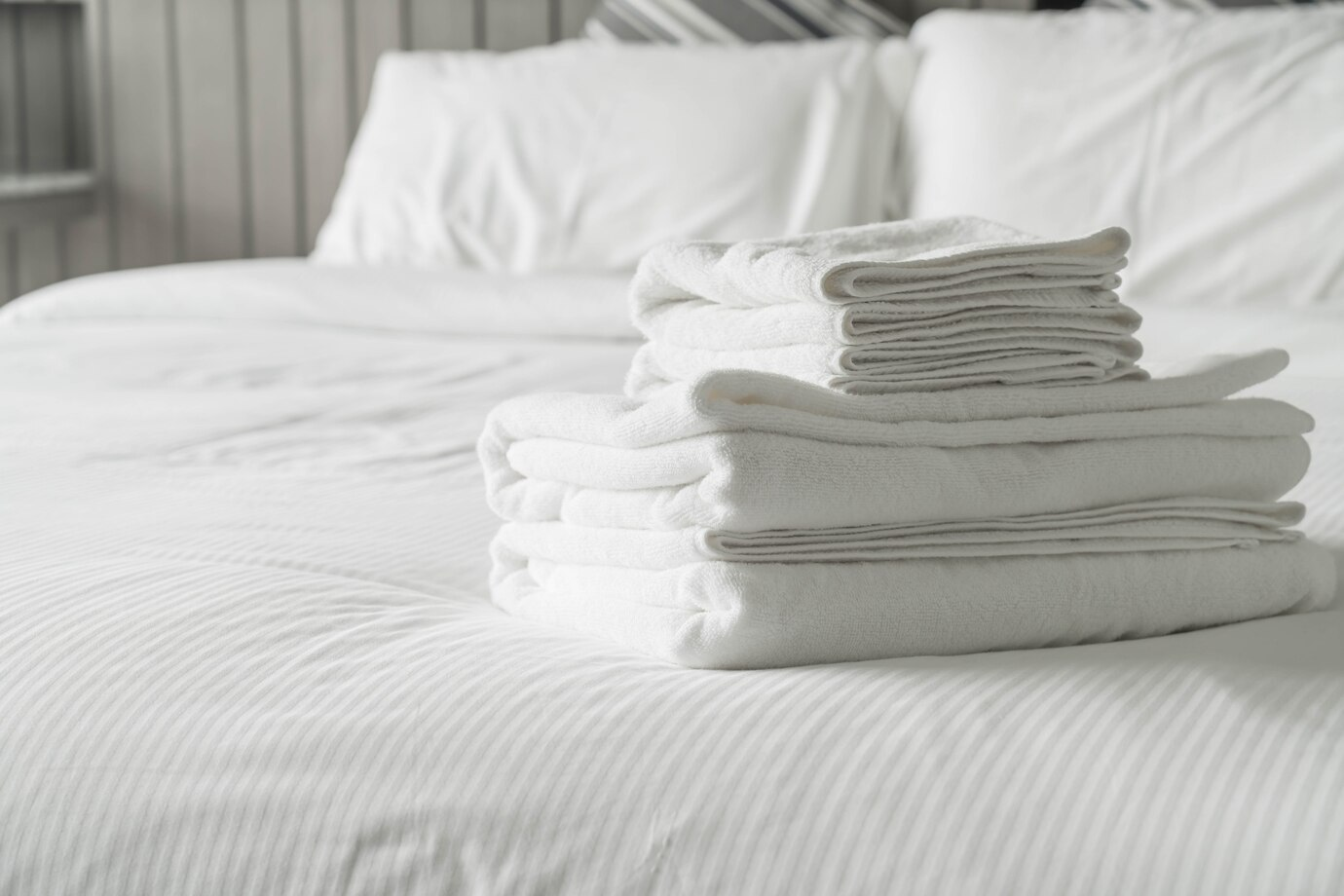 Folded white towels on a hotel bed