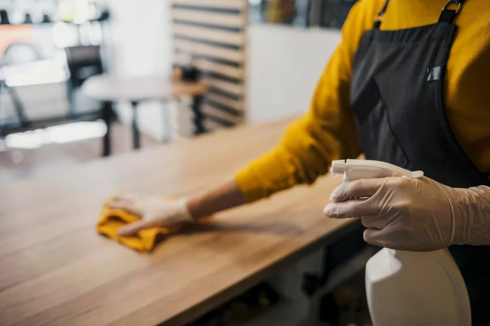 Staff wiping down a counter with cleaning spray and cloth
