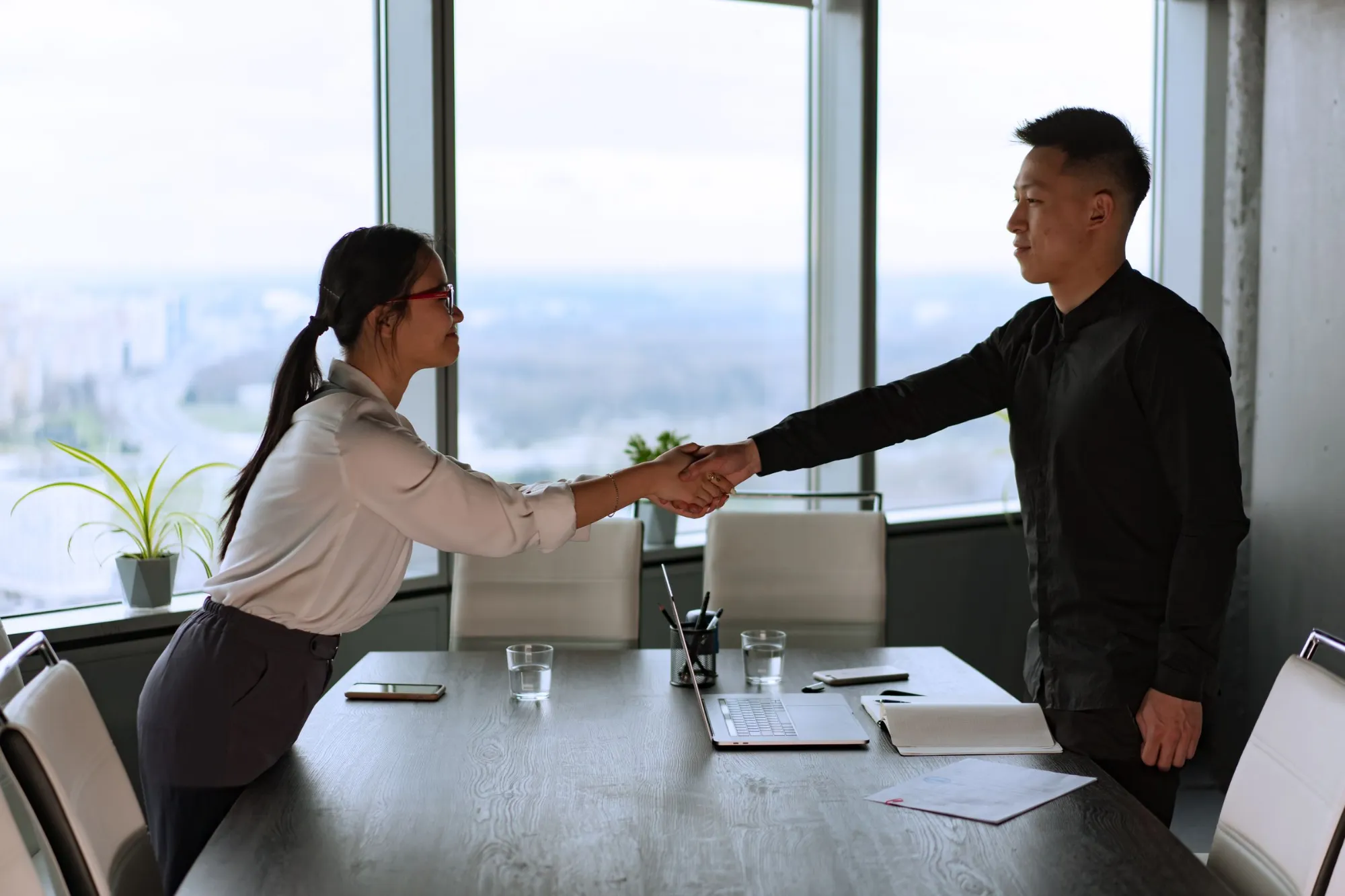 Two business partners shaking hands in a meeting room