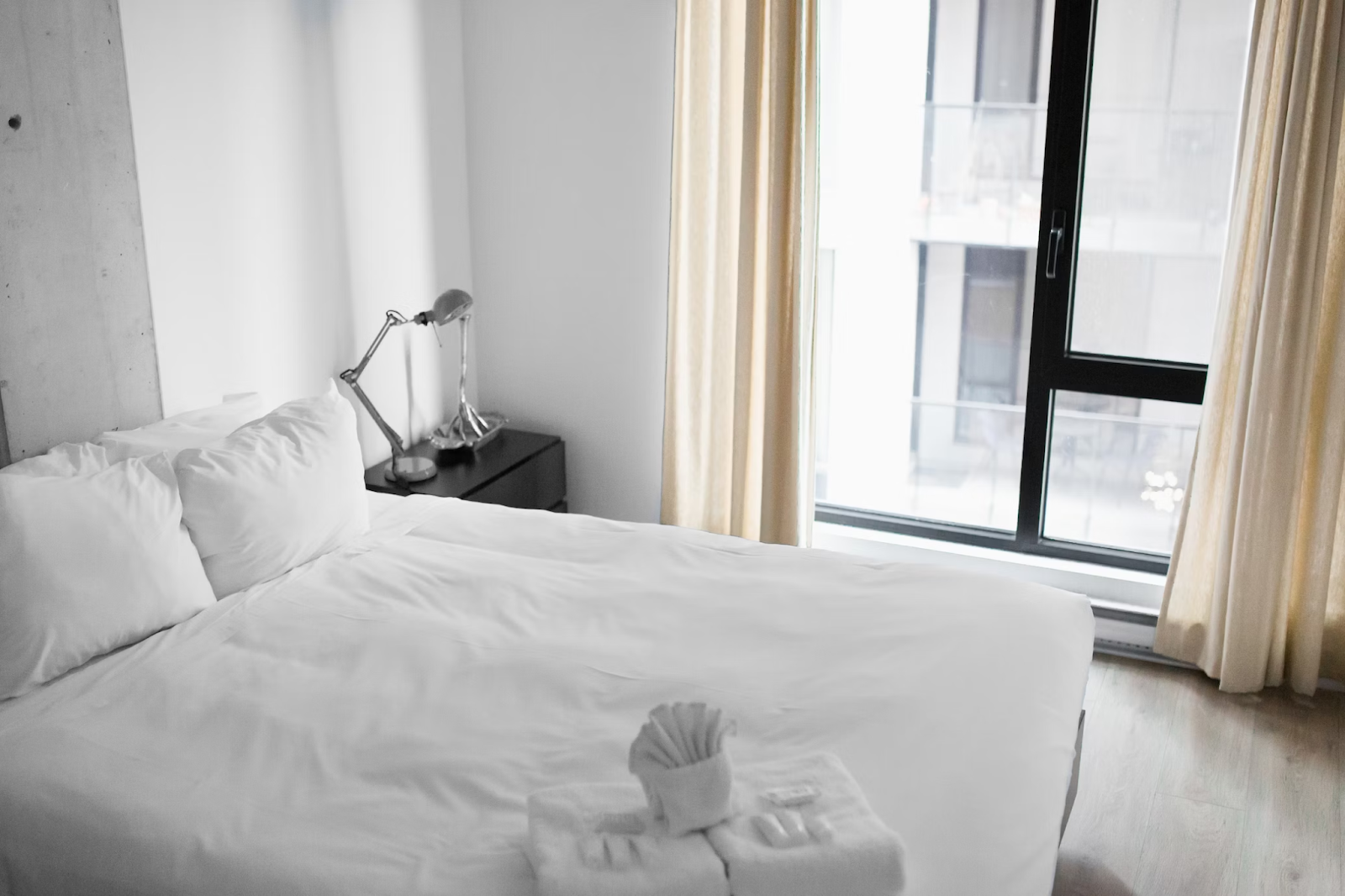 Hotel bedroom with a made bed by the window