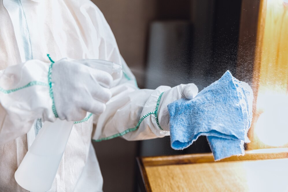 Cleaner in protective clothing wiping a surface