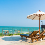 Resort pool deck with loungers and an umbrella by the sea