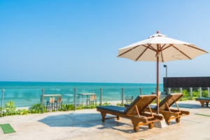 Resort pool deck with loungers and an umbrella by the sea