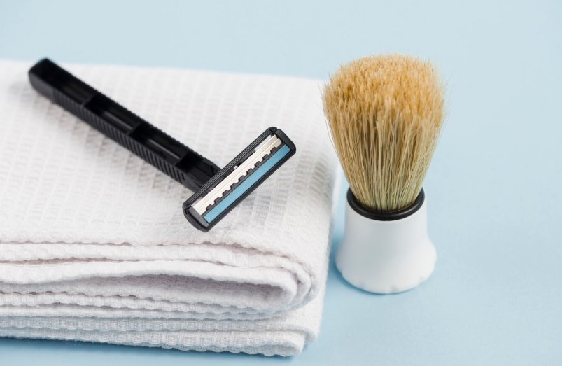 Razor and shaving brush on a folded white towel
