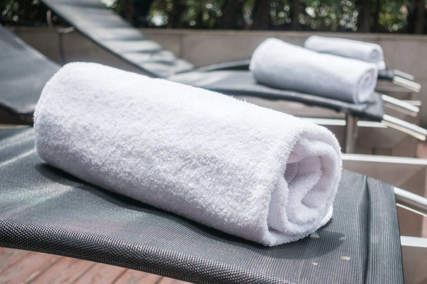 Rolled white towels on a poolside lounger